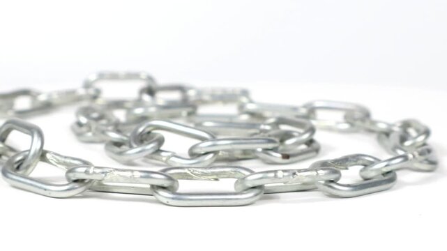 A steel chain spirals across the frame against a white background. On a rotating plate.