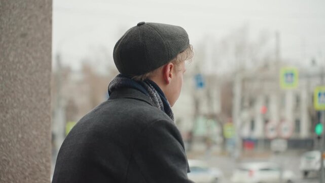 Hopeful city portrait white creator smiling with gentle expression by concrete column, light snow flakes on hair, warm skin tones, intimate closeup and cinematic shallow focus conveying optimism