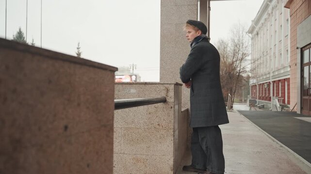 Wide shot white creator leaning on railing, caucasian writer figure watching rainsoaked boulevard, profile closeups reveal pensive gesture, muted autumn palette, narrative mood and quiet contemplation