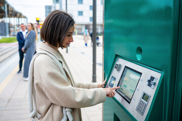 Woman buying public transport ticket at terminal kiosk