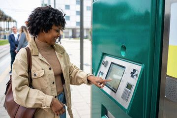 Woman purchasing public transport ticket at vending machine