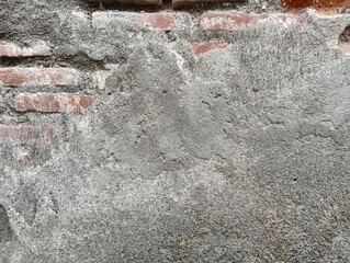 Close-up of a damaged, old concrete wall with peeling plaster and exposed brickwork. The rough, textured surface provides an abstract background useful for construction, decay, or urban themes.  © Din_Wic