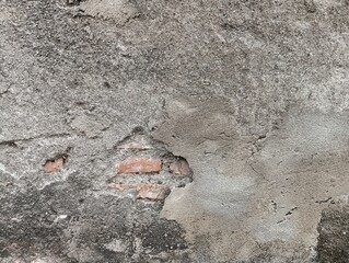 Close-up of a damaged, old concrete wall with peeling plaster and exposed brickwork. The rough, textured surface provides an abstract background useful for construction, decay, or urban themes.  © Din_Wic