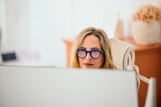 Professional woman wearing blue glasses concentrating at work