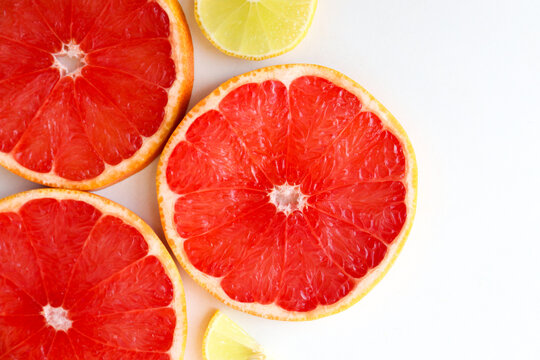 Freshly cut grapefruit slices isolated on a white background, bright pink or red citrus fruit pieces with juicy texture, healthy natural food concept.