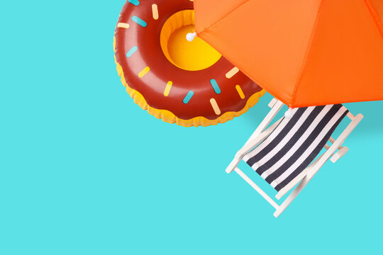 Striped beach chair and donut float under an umbrella