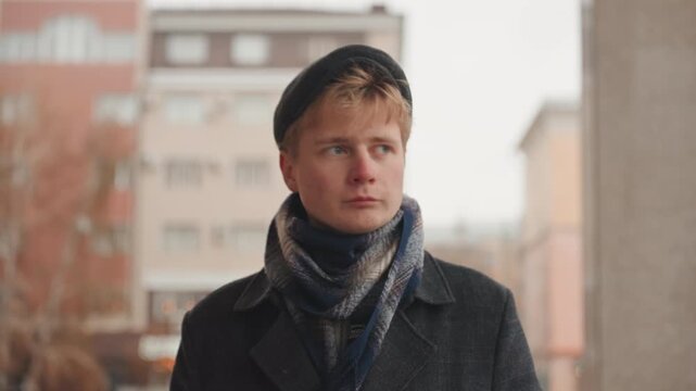 Street fashion captured in silence. Casual city moment captured with layered clothing and architecture. Quiet cinematic scene featuring person in layered attire observing city surroundings