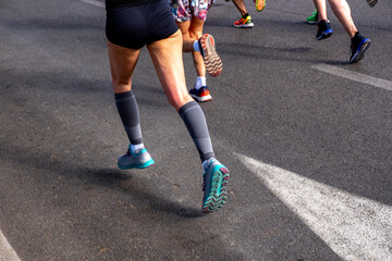 Obraz premium Female runner in legs compression socks running in group of athletes