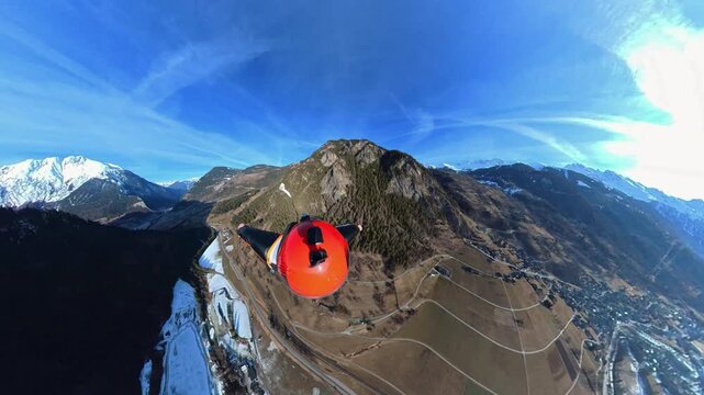 Wingsuit BASE jumper flying over Verbier surrounded by alpine mountains with snow-covered peaks. High-speed flight, dramatic scenery, and cinematic extreme sports action in the Swiss Alps.