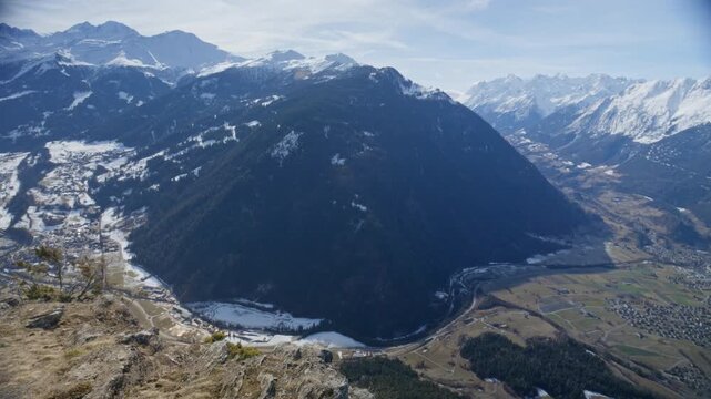 Wingsuit BASE jumper flying over Verbier surrounded by alpine mountains with snow-covered peaks. High-speed flight, dramatic scenery, and cinematic extreme sports action in the Swiss Alps.