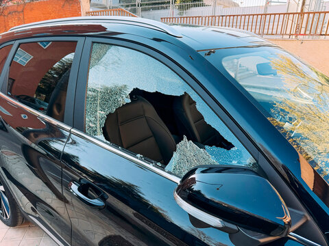 Broken car side window with shattered glass edges.