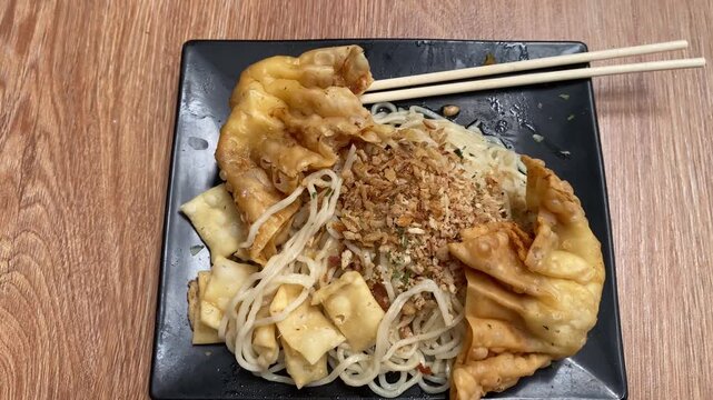 Indonesian fried noodles with fried wontons served on a plate