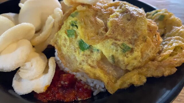 Indonesian fried egg omelette with rice and crispy crackers
