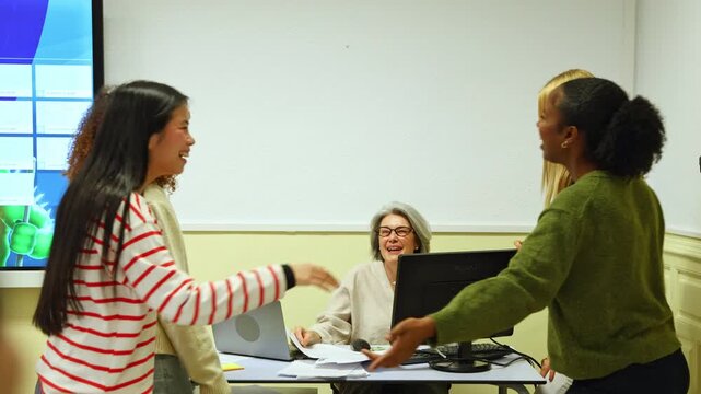 Multiethnic students teasing and laughing with teacher in classroom