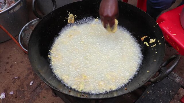 Close up shot of spicy stuffed chili fritters sizzling in hot vegetable oil during traditional snack preparation.