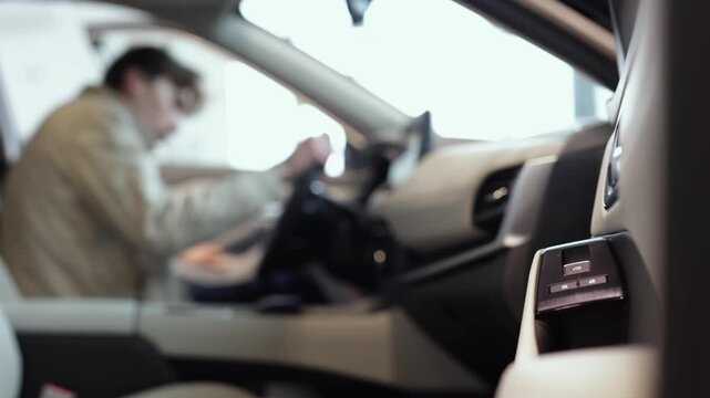 Man exploring new car interior in dealership showroom. Car buying and selection concept.

