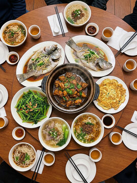 A vibrant, top-down "flat lay" of a large, diverse Taiwanese feast round table. In the center is a big clay pot of Three Cup Chicken (三杯雞) , surrounded by various other dishes like a whole steamed fis