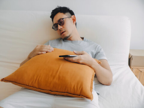Comfortable relaxed posture of asian man resting with pillow and phone