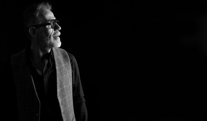 Profile portrait, waist up of a mature man in low key, black and white © Curto