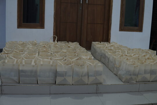 Rows of cream-colored fabric goody bags neatly arranged on a house porch for a community event.