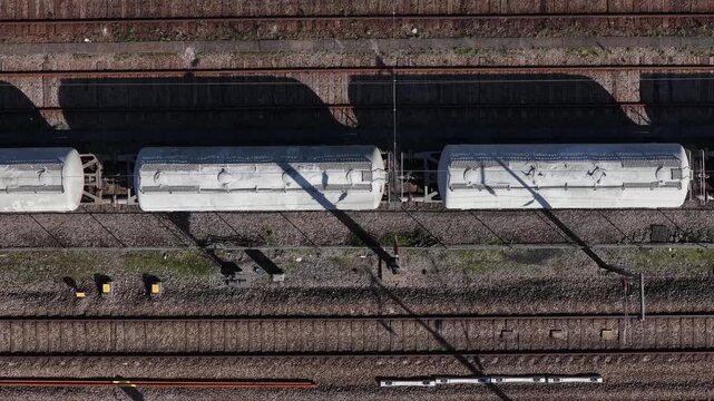 Aerial view of train wagons parked on multiple parallel rails, with shadows cast by the wagons and overhead equipment, Porto, Portugal.