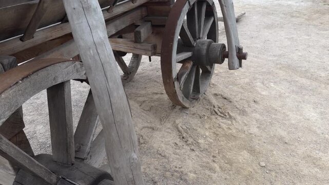 Wooden spokes and metal axle of a wagon wheel on sandy ground