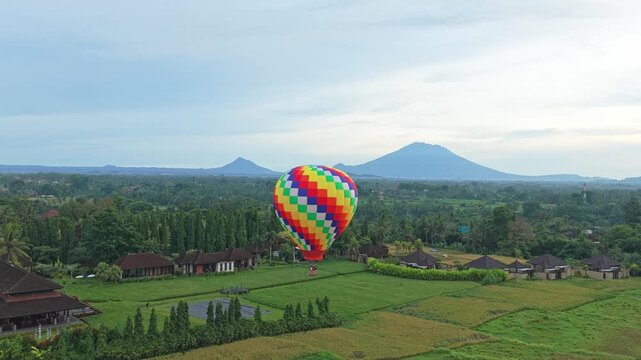 Colorful hot air balloon flying over bali rice fields with volcanoes
