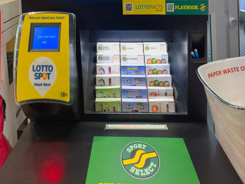 Calgary, Alberta, Canada. April 9, 2026. A self-service lottery ticket checker and selection booth featuring various game slips at a retail outlet.