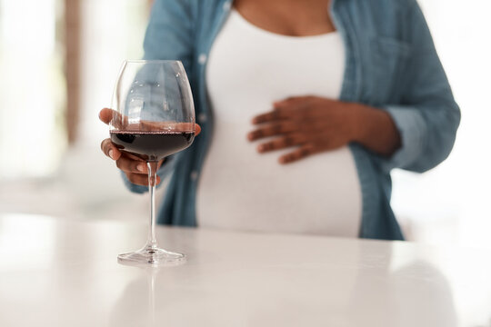 Addiction, pregnancy and hands in house with wine, bad habit and awareness in maternal health. Risk, prevention and woman in home with alcohol, fetal development or substance abuse in prenatal care.