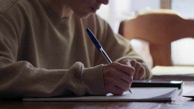 Woman Writing in a Notebook with a Pen at a Table
