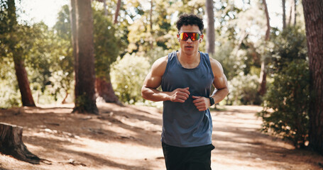 Obraz premium Running, fitness and man with sunglasses in nature for training, exercise and workout for cardio. Sports, athlete and person on outdoor trail for active hobby, endurance and wellness for health