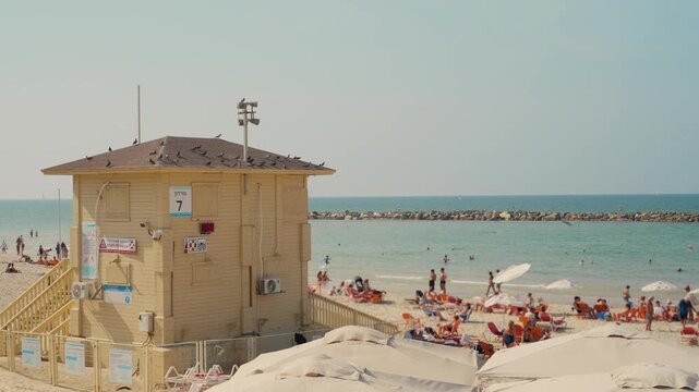 Lifeguard hut or station in Tel Aviv beach in Israel on hot summer day outdoors. Local people and tourists enjoy the heat swimming in the fresh Mediterranean Sea water and sunbathe on sandy beach