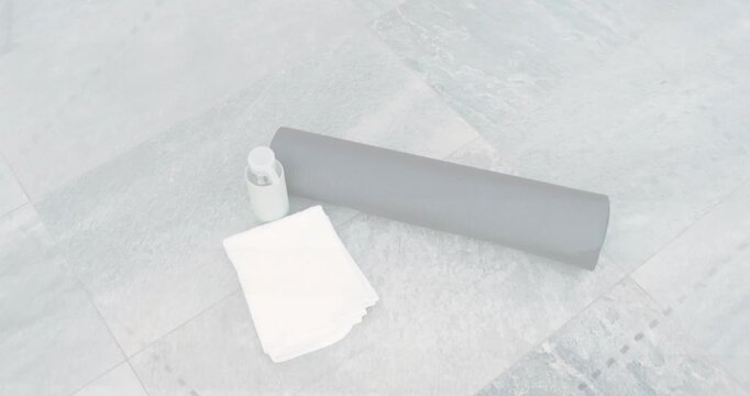 Camera panning and rotating, showing mat, towel, bottle on tiled floor, implying exercise prep