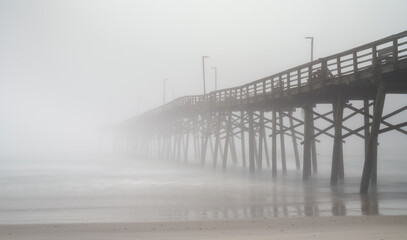 Fototapeta premium view of the Surf City fishing pier and beach during a spring morning with thick fog