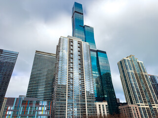 Obraz premium Skyscrapers rising in a city skyline on a cloudy day with modern structures and glass façades in an urban environment
