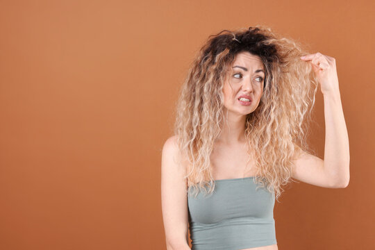 Unhappy woman with tangled damaged hair on brown background, space for text