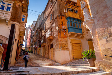 Fototapeta premium Traditional Maltese street with people walking, Valetta.