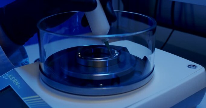 Applying lubricant to steel ball bearing on precision scale in laboratory environment