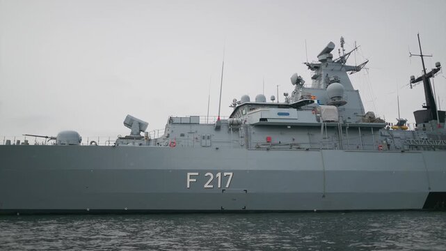 A military battleship, f 217, is shown in slow motion footage. camera pans left across ship.