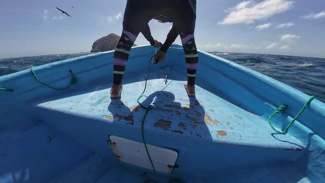 Focused fisherman riggs green ropes and a pink buoy on a traditional blue boat, navigating the vibrant turquoise waves of the Caribbean.