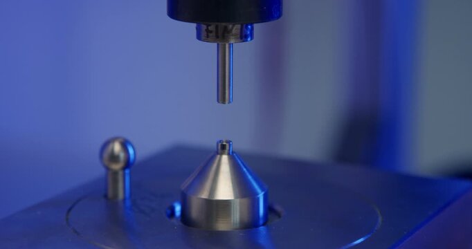 Mechanical material testing machine performing a hardness test on a metal component in a laboratory