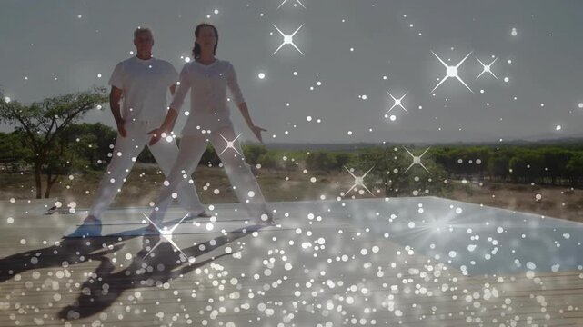 Duo stepping into wide pose over pool, showing torsos, opening arms, sparkling over pair, fitness