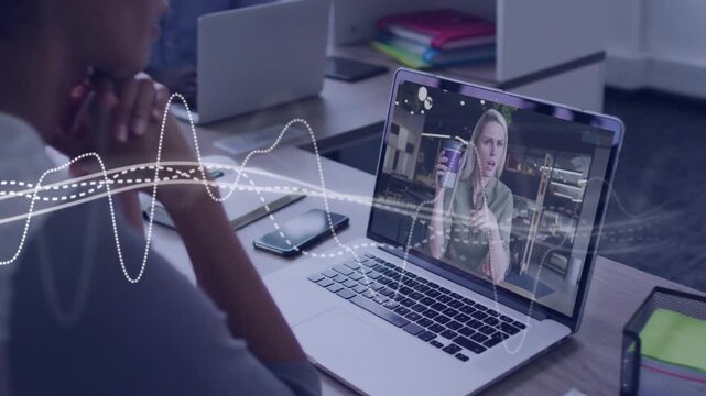 Worker watching laptop as peer raising cup and gesturing, waveform moving across frame for business