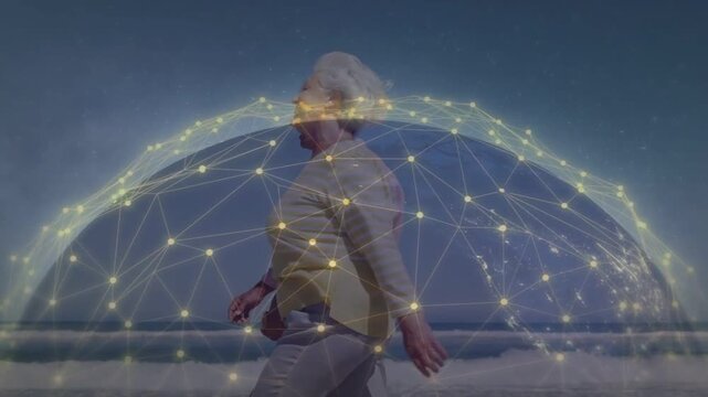 Vertical video: Walking senior couple in shirts entering left moving along beach under network dome