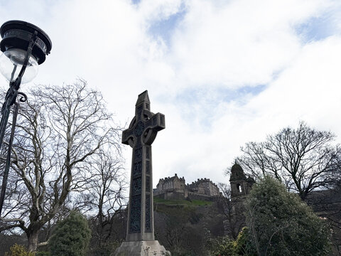 Celtic cross Dean Ramsay monument framed against Edinburgh Castle and winter trees in Princes Street Gardens, Edinburgh, Scotland, UK