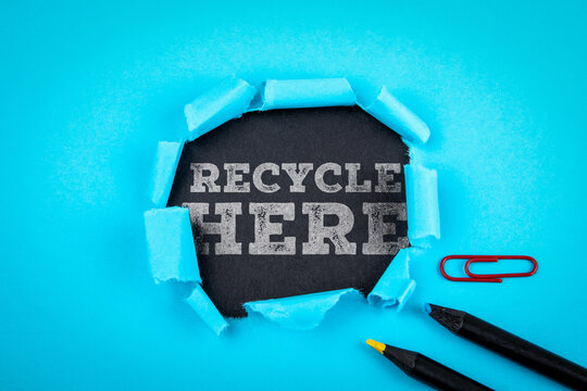 Recycle Here Text Revealed Through Torn Paper on Blue Background