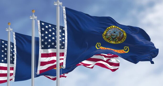 Idaho state flags waving along with the national flags of the United States of America on a clear day. Seamless 3d render animation. Slow motion loop. Selective focus