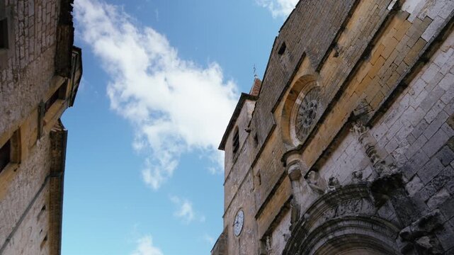 Ancient church entrance and stone masonry walls in the village of Monpazier, Dordogne. Low angle tracking shot in slow motion.
