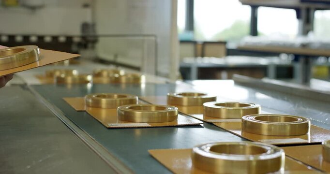 Technician picking up packaged industrial ball bearings from a production line conveyor
