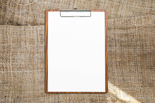 Blank white paper on wooden clipboard with space on hessian fabric texture background, business and education object